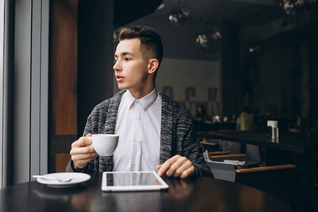 Mann mit Tablette und Kaffee in einem Café