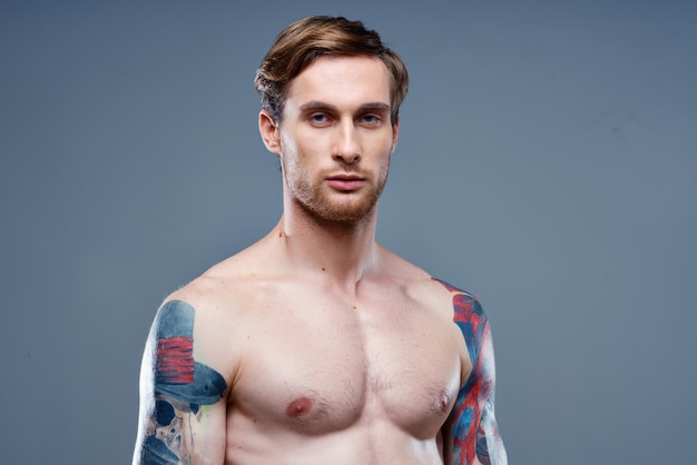Mann mit Tätowierung nackter Rumpf Sport Fitness grauer Hintergrund Porträt Hochwertiges Foto
