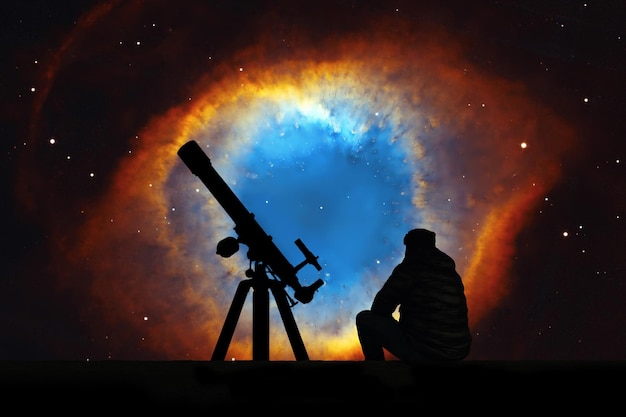 Mann mit Teleskop, das die Sterne betrachtet. Der Helixnebel oder NGC 7293 im Sternbild Wassermann. Elemente dieses Bildes werden von der NASA bereitgestellt.