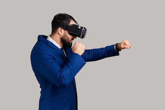 Mann mit Virtual-Reality-Brille auf dem Kopf, der ein Kampfspiel spielt und die geballten Fäuste zum Boxen bereit hält