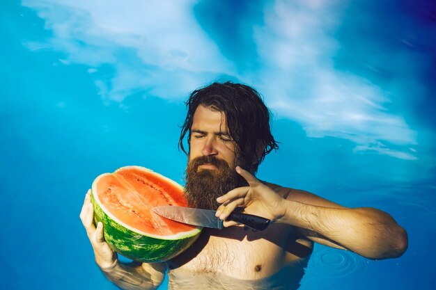 Mann mit Wassermelone und Messer im Pool