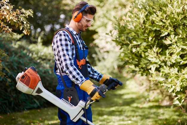 Mann mit Weedwacker beim Grasmähen