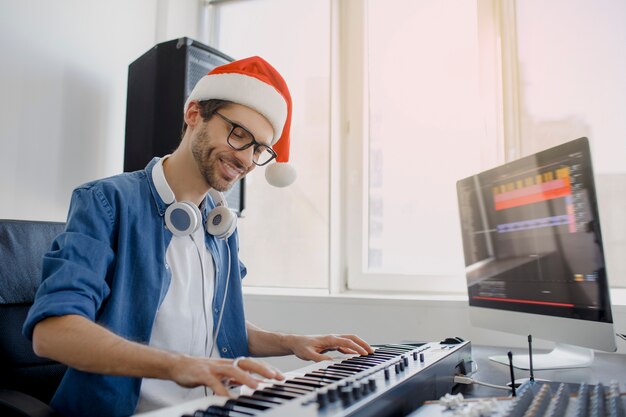 Mann mit Weihnachtsmütze, die Klavier im Studio spielt