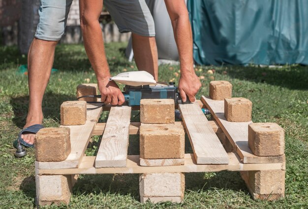 Foto mann mit werkzeugen arbeitet mit holzwerkstoffen, die möbel in der natur bauen und reparieren