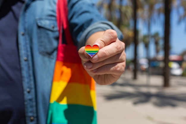 Mann mit wiederverwendbarer Regenbogentasche und LGBT-Abzeichen Stolzmonat