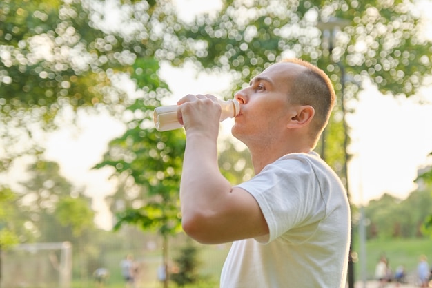 Mann mittleren Alters, der Milch trinkt, Milchprodukt von der Flasche im Freien