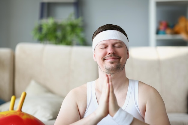 Mann mittleren Alters, der zu Hause meditiert, legt die Hände in die Namaste-Geste
