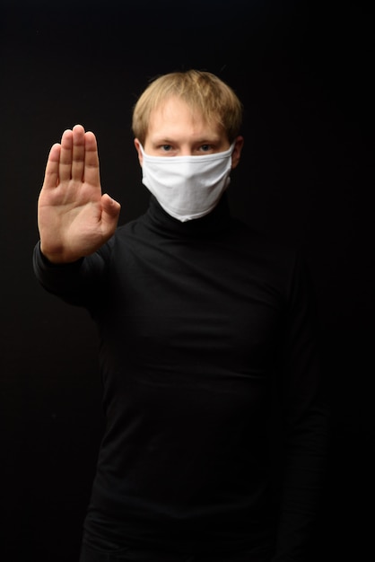 Mann mittleren Alters in einer medizinischen Maske zeigt einen Stopp mit der Hand. Das Konzept des Schutzes gegen Coranavirus.