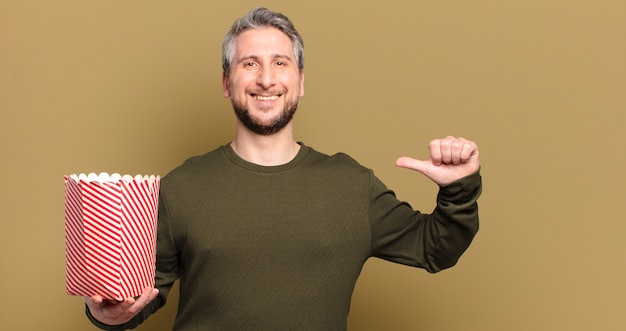 Mann mittleren Alters mit einem Popcorn-Eimer