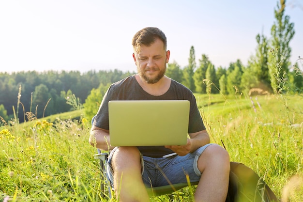 Mann mittleren Alters mit Rucksäcken mit Laptop in der Natur