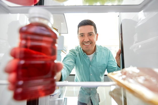 Mann nimmt Saft aus dem Kühlschrank in der Küche zu Hause