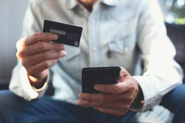 Mann nutzt Handy und Kreditkarte für Online-Shopping und Internetzahlungen über digitale mobile Banking-App