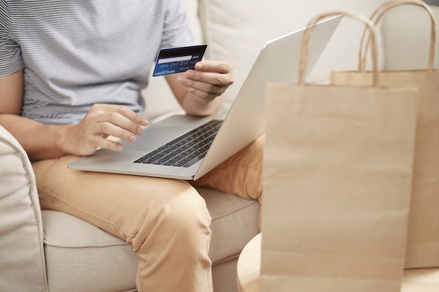 Mann Online-Shopping mit Laptop und Rückseite Kreditkarte e Brieftasche a