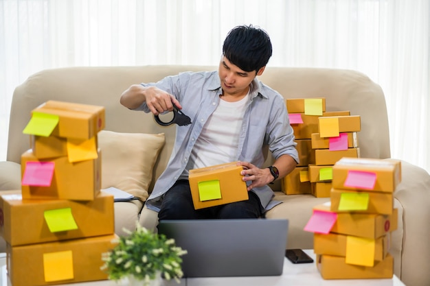 Mann Online-Unternehmer mit Klebeband zum Verpacken der Paketbox zu Hause Büro, bereiten Produkt für die Lieferung an den Kunden