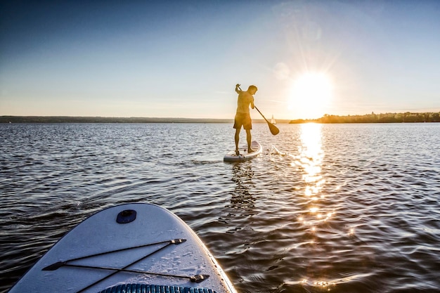Mann paddleboardt im Meer gegen den Himmel bei Sonnenuntergang