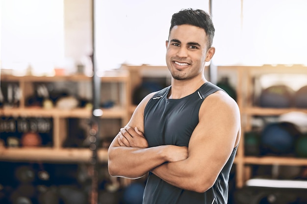 Mann Porträt und Selbstvertrauen in der Turnhalle für Fitness Krafttraining und Übung für Muskelentwicklung oder -wachstum Männliche Person Arme gekreuzt und glücklich im Sportzentrum für körperliches Cardio und Workout