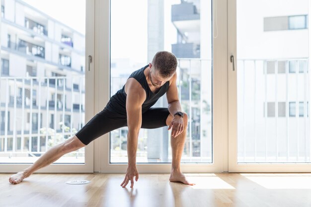 Mann praktiziert Yoga in seinem Haus