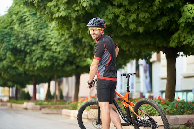 Mann Radfahrer lächelnd über die Schulter posierend in der Nähe von Fahrrad