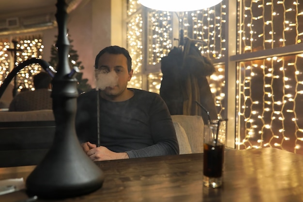 Mann raucht Wasserpfeife in einem Nachtcafé