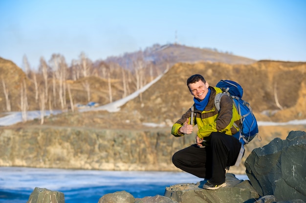 Mann Reisender mit einem Rucksack zeigt Daumen auf dem See