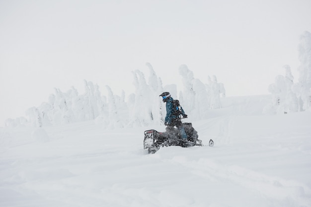 Mann Reiten Schneemobil in den schneebedeckten Alpen