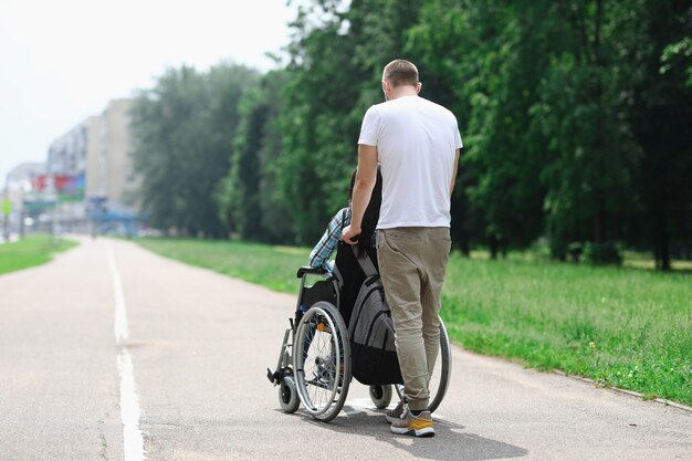 Mann rollt Rollstuhl mit Mädchen unten Straße.