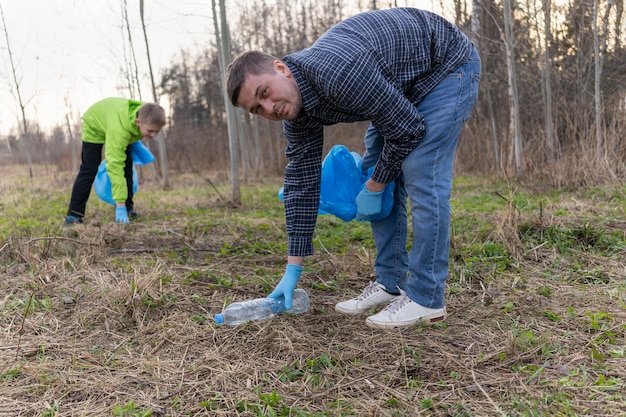 Mann sammelt Müll in blauen Müllsäcken als Freiwilliger, die den Wald reinigen