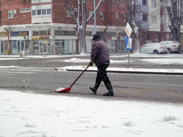 Mann schaufelt Schnee von der Straße