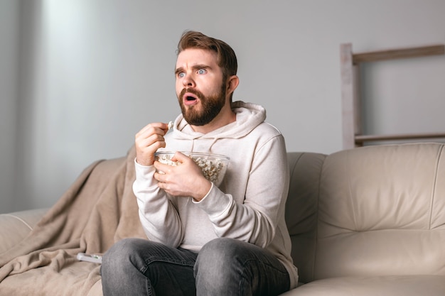 Mann schaut sich Filme an, die zu Hause auf einer Couch sitzen