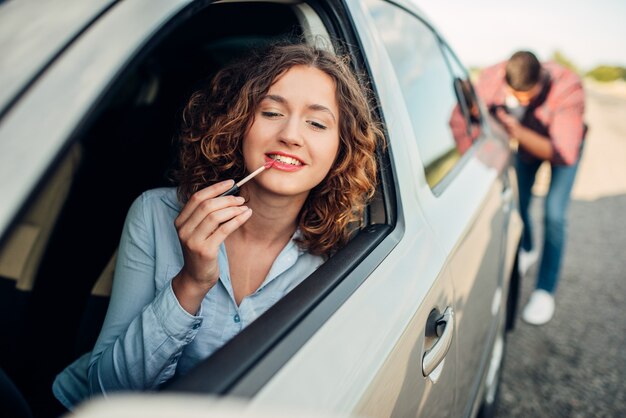 Mann schiebt ein kaputtes Auto, Fahrerin