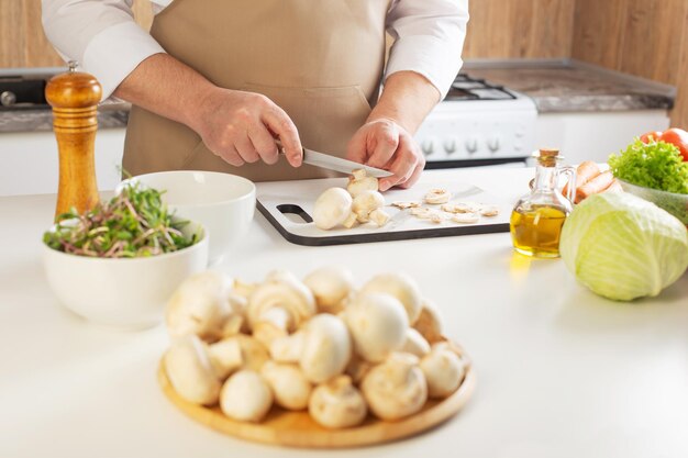 Mann schneidet Champignons auf dem Tisch in der Küche