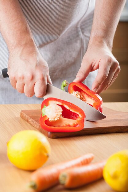 Mann schneidet Paprika in der Küche