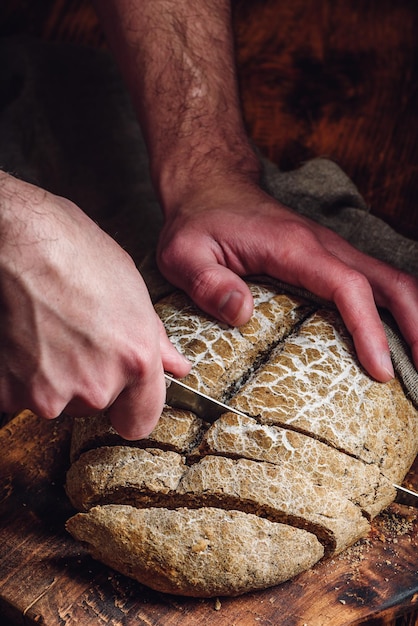 Mann schneidet Roggenbrot