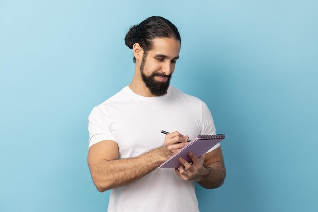 Mann schreibt Aufgabenliste auf und macht sich mit Stift Notizen im Notizbuch, um den Zeitplan zu überprüfen