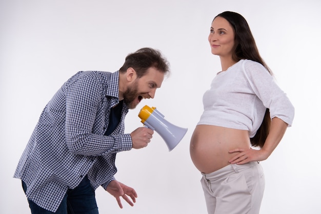 Mann schreit im Megaphon auf schwangeren Bauch der Frau