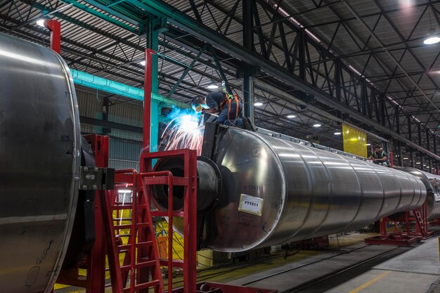 Mann schweißt großen Stahltank in der Fabrik