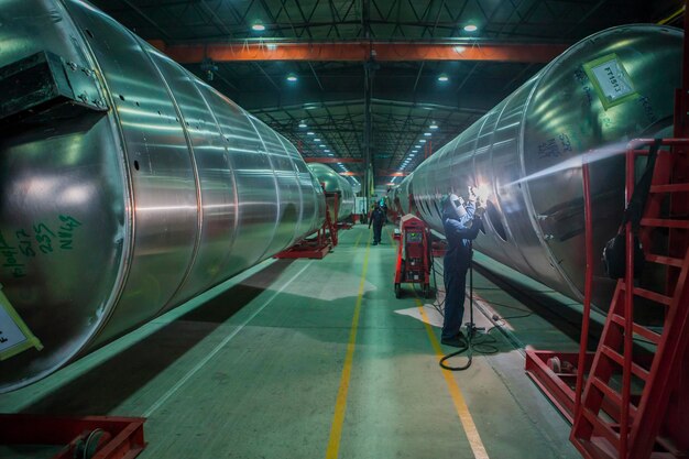 Foto mann schweißt großen stahltank in der fabrik