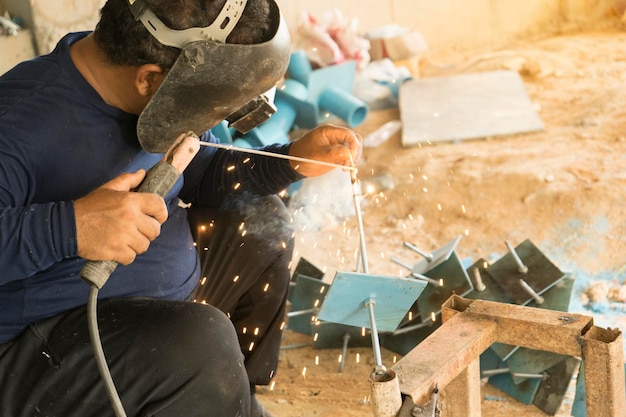 Foto mann schweißt metall in der werkstatt