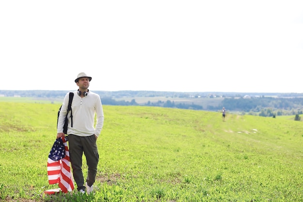 Mann schwenkt die amerikanische Flagge, die im landwirtschaftlichen Bereich der Grasfarm steht, Feiertage, Patriotismus, Stolz, Freiheit, politische Parteien, Einwanderer