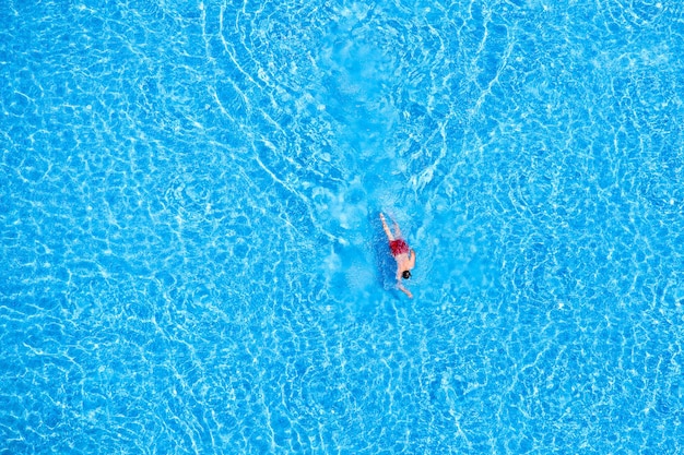 Mann schwimmt im Pool des Hotels. Blick von oben