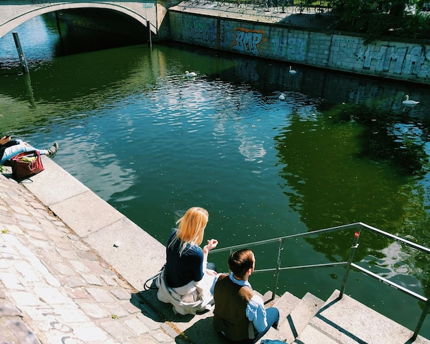 Mann sitzt auf Bank im See