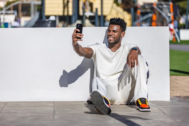 Mann sitzt auf dem Boden und macht ein Selfie