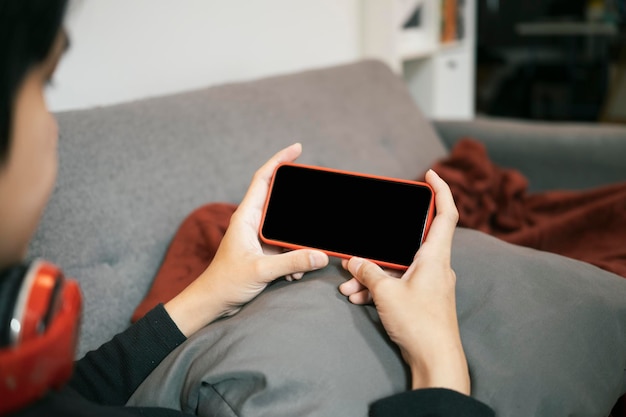 Mann sitzt auf dem Sofa und sieht sich etwas auf dem Handy an