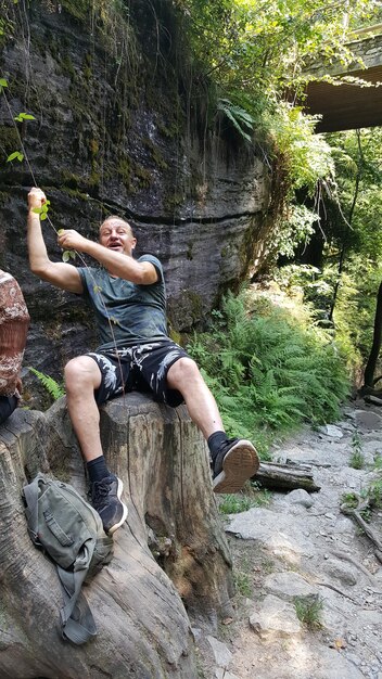 Mann sitzt auf einem Felsen im Wald