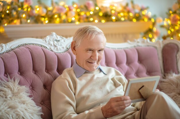 Mann sitzt auf einem Sofa und betrachtet Foto