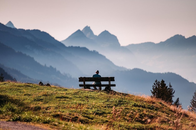 Foto mann sitzt auf einer bank gegen die bergkette