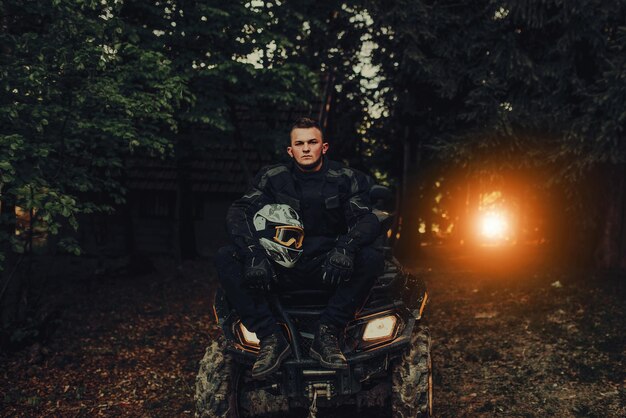 Mann sitzt auf Quad im Wald und bereitet sich auf Fahrt vor