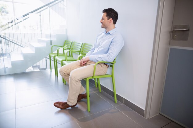 Mann sitzt auf Stuhl im Krankenhauskorridor