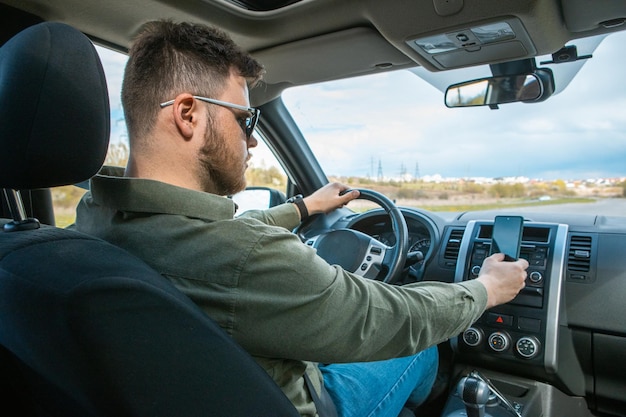 Mann sitzt im Auto mit Telefon