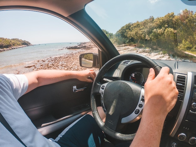 Mann sitzt im Auto und fährt in der Nähe des Sommerstrandes